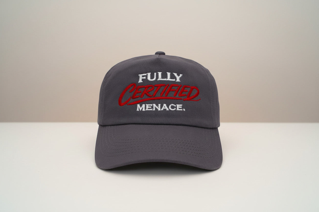 The Cap Shack charcoal grey 5-panel cotton cap with "FULLY CERTIFIED MENACE." embroidered in white and red. Pre-curved peak.