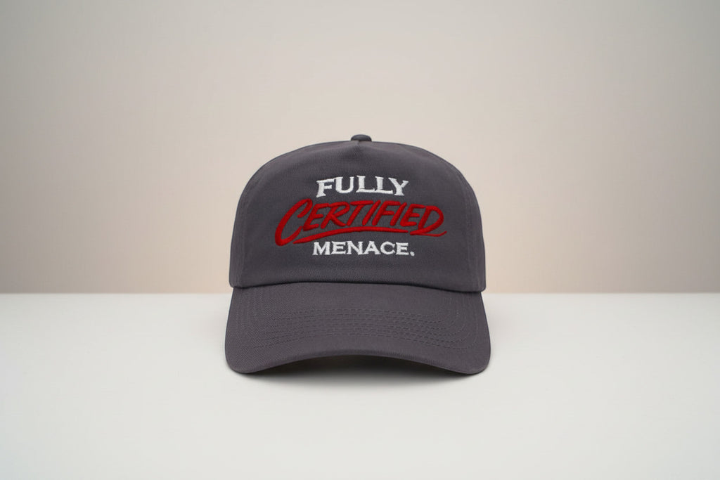 The Cap Shack charcoal grey 5-panel cotton cap with embroidered "FULLY CERTIFIED MENACE." in red and white. Pre-curved peak.